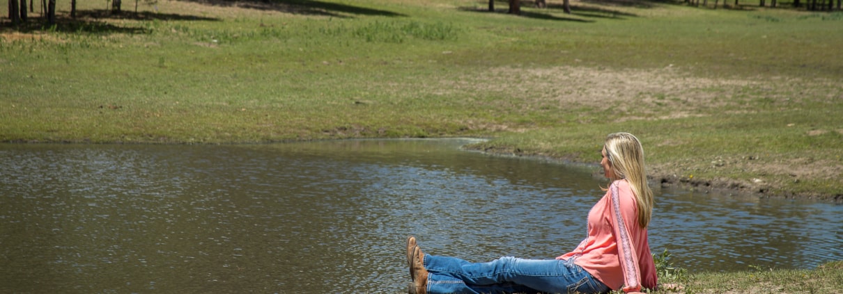 Female in a pink shirt sitting by the pond