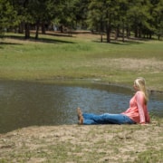 Female in a pink shirt sitting by the pond