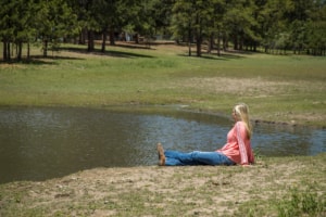 Female in a pink shirt sitting by the pond