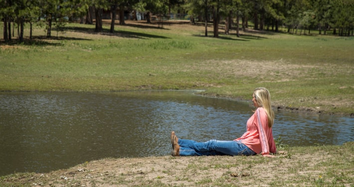 Female in a pink shirt sitting by the pond